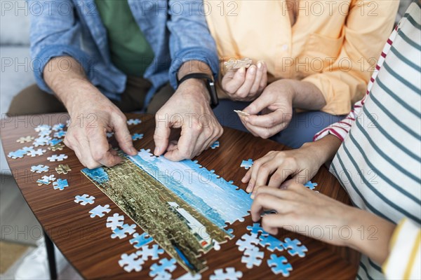 Close up people doing puzzle together