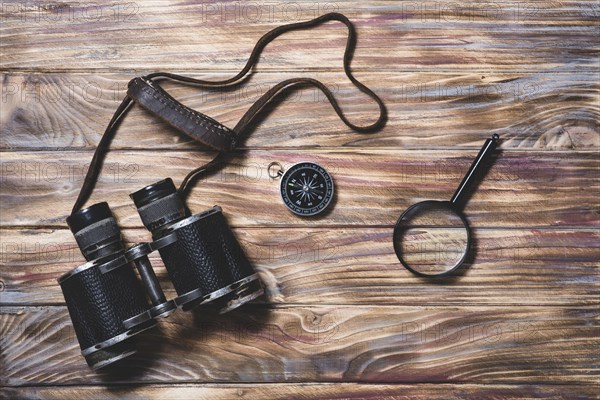 Wooden background with binocular compass magnifying glass