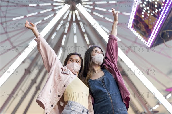 Female friends with masks amusement park