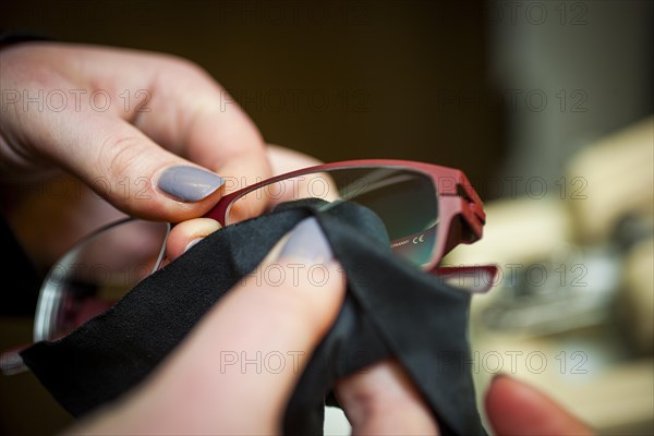 A woman cleans a pair of glasses