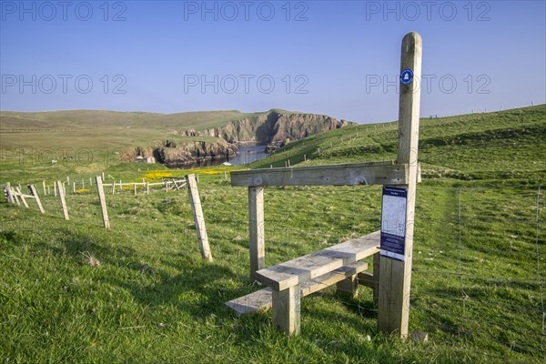 Wooden stile crossing on fence along the spectacular coastline with sea cliffs and stacks at Westerwick