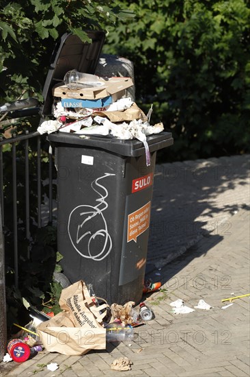 Overfilled dustbin for residual waste standing on the street