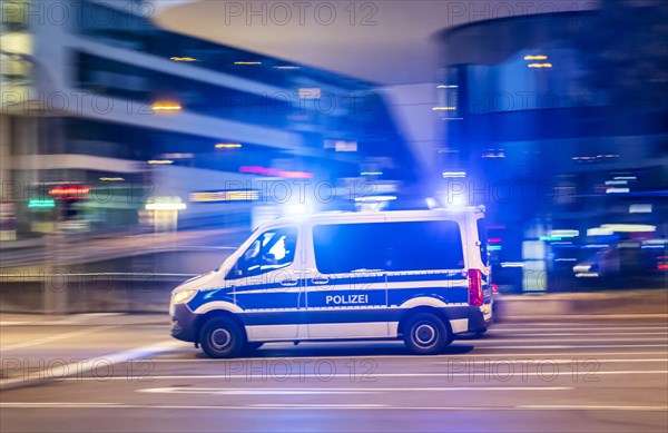 Police vehicle with blue lights at night in front of urban surroundings