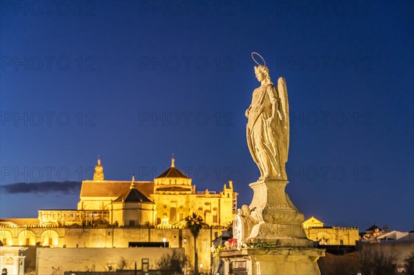 Statue of the Archangel Raphael on the Roman Bridge and the Mezquita at dusk