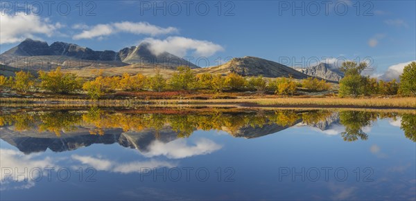 The mountains Hogronden and Digerronden reflected in water of lake in autumn