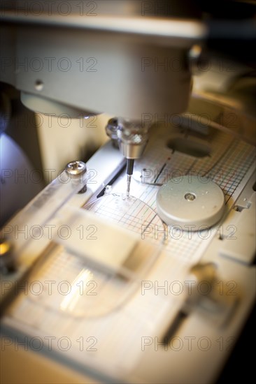 An optician drills a hole in a lens for the temple of a pair of glasses