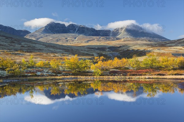 The mountains Hogronden and Digerronden reflected in water of lake in autumn