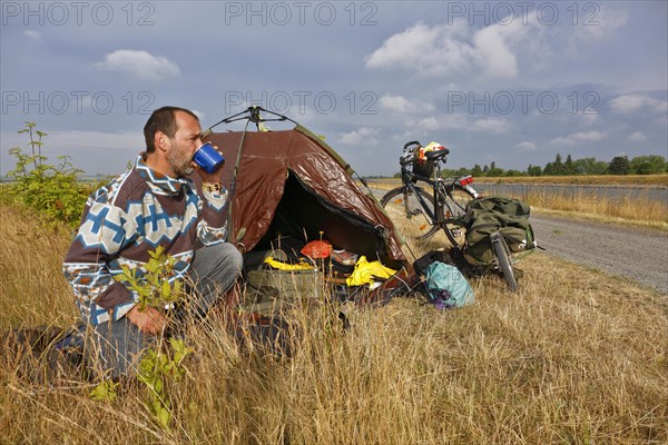 Cycle tourist drinking a coffee in front of his tent