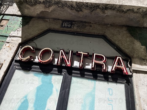 Old neon sign Contra on a house in Lisbon