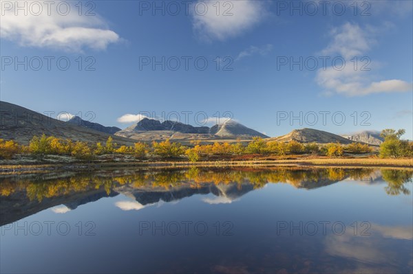 The mountains Hogronden and Digerronden reflected in water of lake in autumn