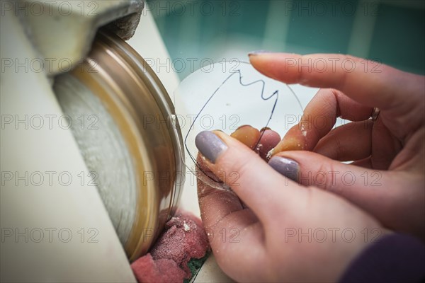 A woman grinds a lens at an optician's shop