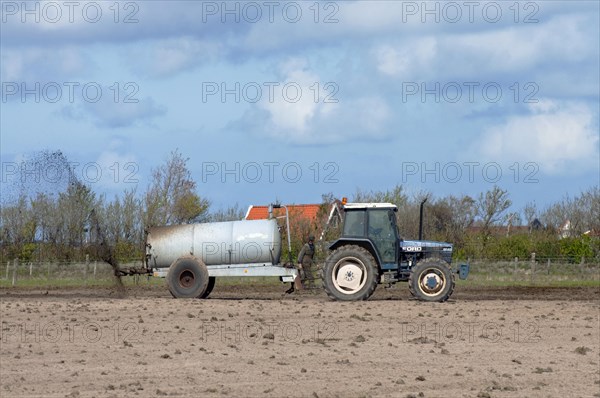 Tractor spreading manure to fertilize field