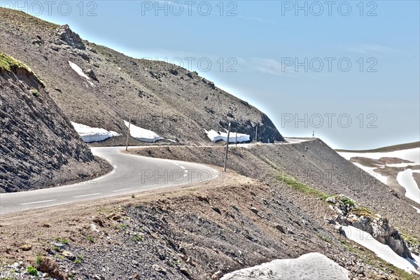 Photo with reduced dynamic saturation HDR of mountain pass alpine mountain road alpine road pass road pass view of highest asphalted alpine road ring road around Cime de la Bonette next to Col de la Bonette in high mountains above tree line