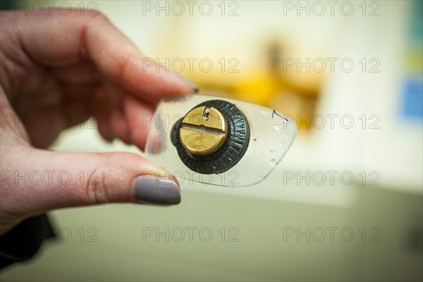 A woman holds a cut spectacle lens in her hand