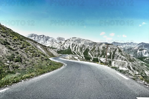 Photo with reduced dynamic range saturation HDR of mountain pass alpine mountain road alpine road pass road pass Col de Raspaillon in French Alps High Alps in high mountains above tree line