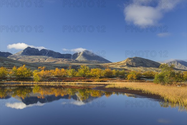 The mountains Hogronden and Digerronden reflected in water of lake in autumn