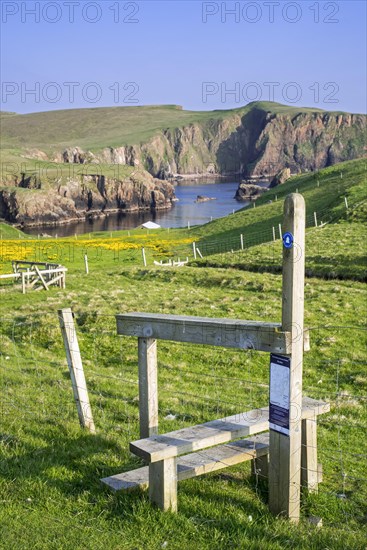 Wooden stile crossing on fence along the spectacular coastline with sea cliffs and stacks at Westerwick