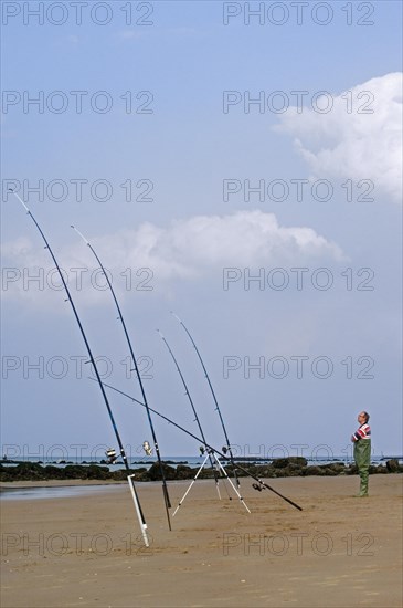 Sea angler with many fishing rods fishing from beach along the North Sea coast