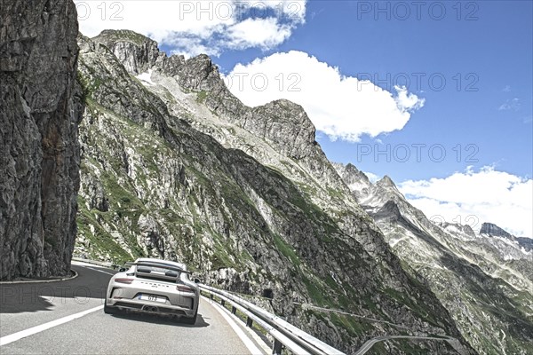 Photo with reduced dynamic range saturation HDR of view of Porsche 911 GT3 driving on mountain road above tree line Alpine pass Mountain pass in high Alps