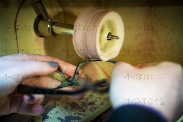 An optician polishes a pair of glasses