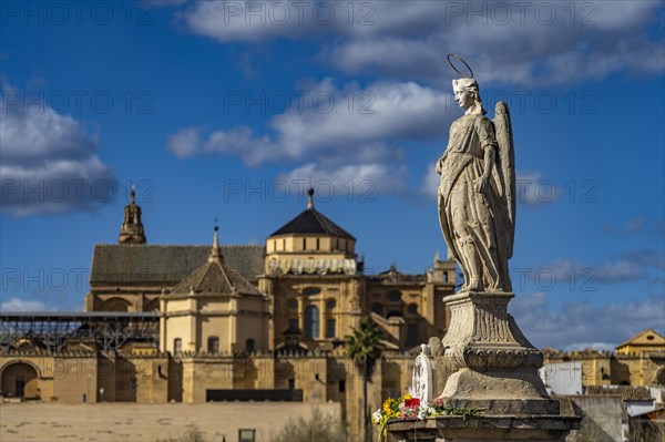 Statue of the Archangel Raphael on the Roman Bridge and the Mezquita in Cordoba