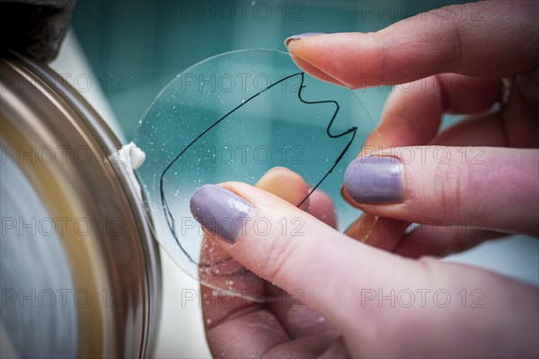 A woman grinds a lens at an optician's shop