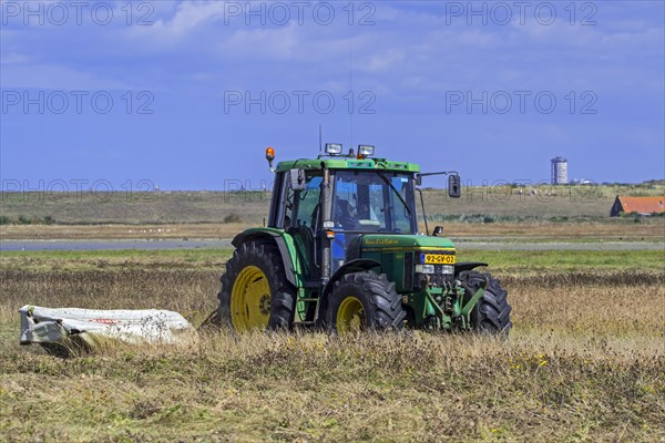 John Deere tractor 6400 with disc mower mowing grass in grassland