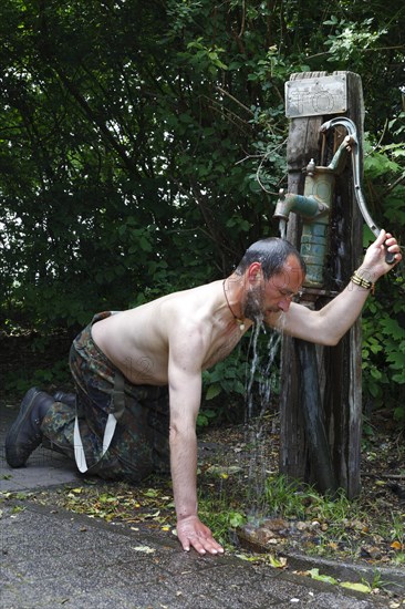 Cycle tourist refreshes himself at a public pump