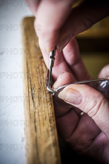 An optician adjusts a temple of a pair of glasses with a screwdriver