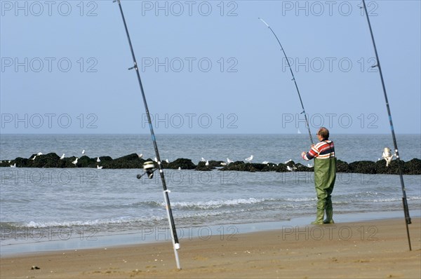Sea angler with many fishing rods fishing from beach along the North Sea coast