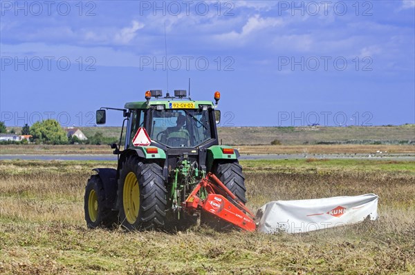 John Deere tractor 6400 with disc mower mowing grass in grassland