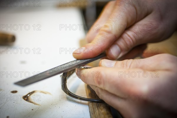 An optician files the frame of a pair of glasses with a file