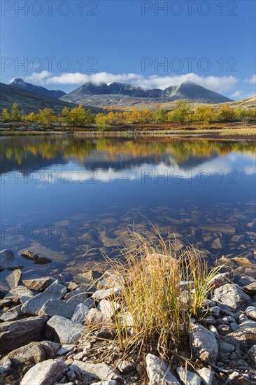 The mountains Hogronden and Digerronden reflected in water of lake in autumn