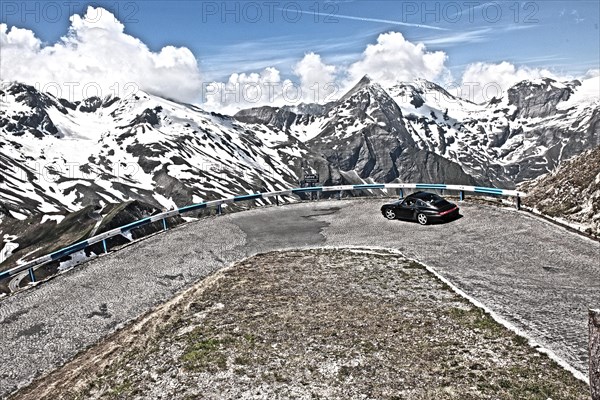 Photo with reduced dynamic range saturation HDR of view of Porsche 911 993 driving into hairpin bend 5 of historic old Grossglockner High Alpine Road Grossglockner-Hochalpenstrasse with cobblestones mountain pass alpine mountain road alpine pass road pass above above tree line