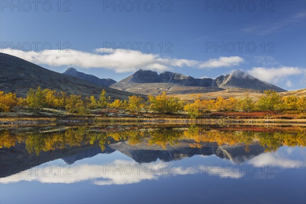 The mountains Hogronden and Digerronden reflected in water of lake in autumn