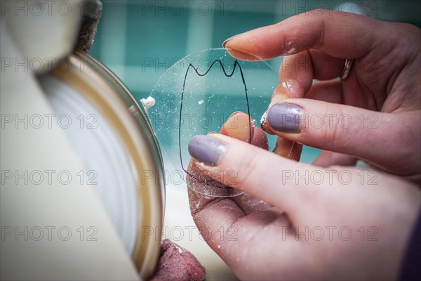 A woman grinds a lens at an optician's shop