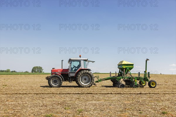 Tractor pulling John Deere 750A no-till seed drill working on farmland