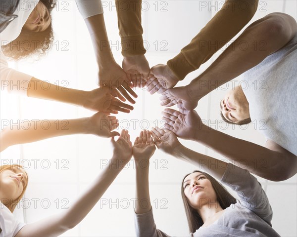 Low view group friends holding hands together