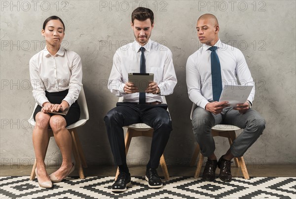 Jealous businesswoman sitting near businessman using digital tablet