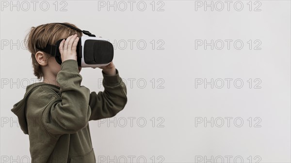 Side view young boy using virtual reality headset with copy space