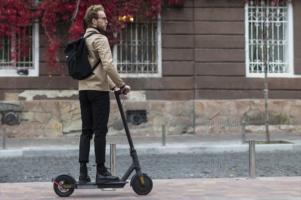 Casual male riding with his electric scooter