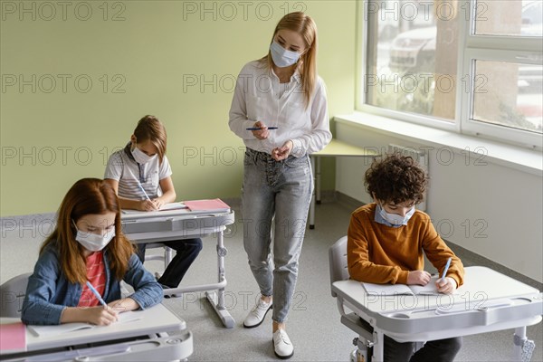 Children with medical masks learning school with teacher