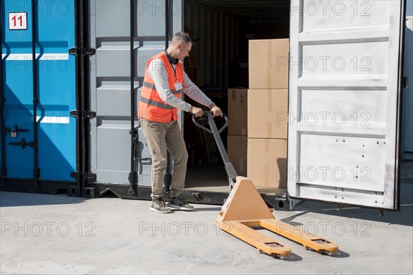 Full shot man carrying pallet truck