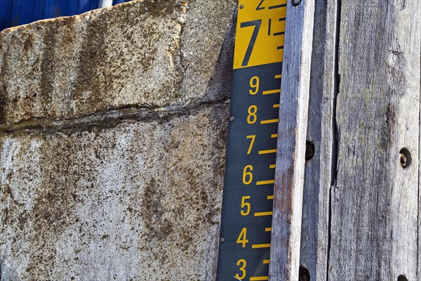 Water level gauge in the harbour basin at high tide and flood