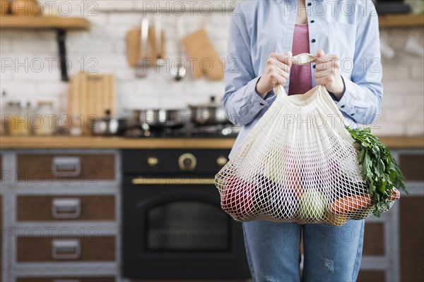 Adult woman holding reusable bag with organic vegetables