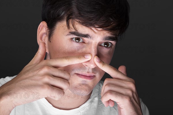 Close up young man touching nose