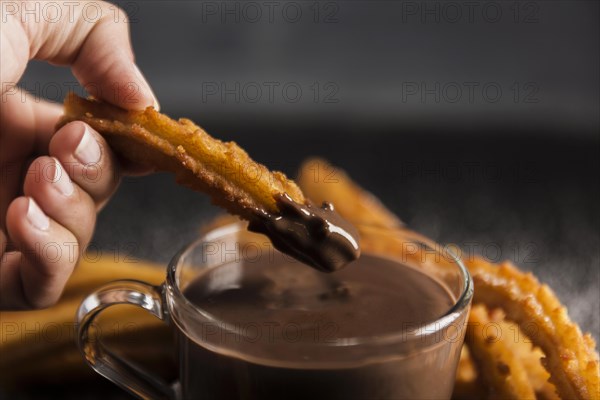 Hand dipping fried churros chocolate