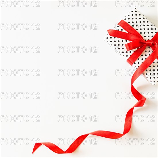 Elevated view gift tied with red ribbon white surface