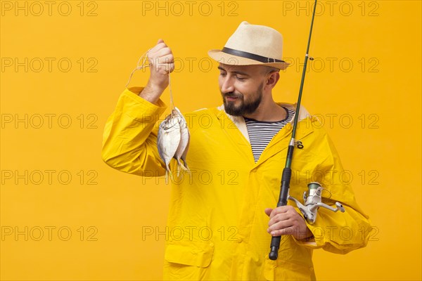 Front view proud fisherman holding catch fishing rod