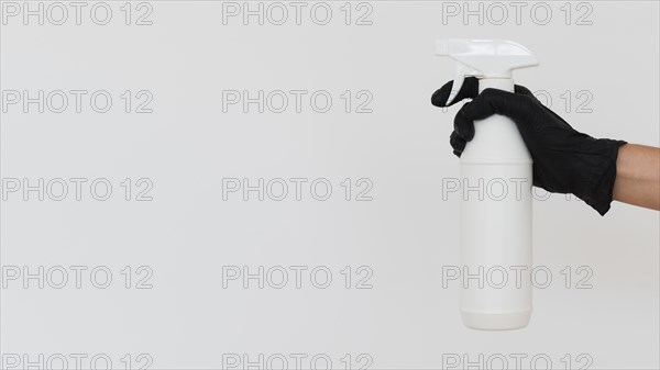 Hand with glove holding disinfectant bottle with copy space